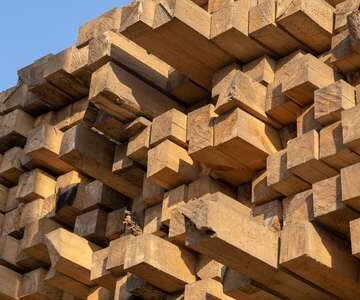 Pine wood timber stack of natural rough wooden boards on building site. Industrial timber building materials